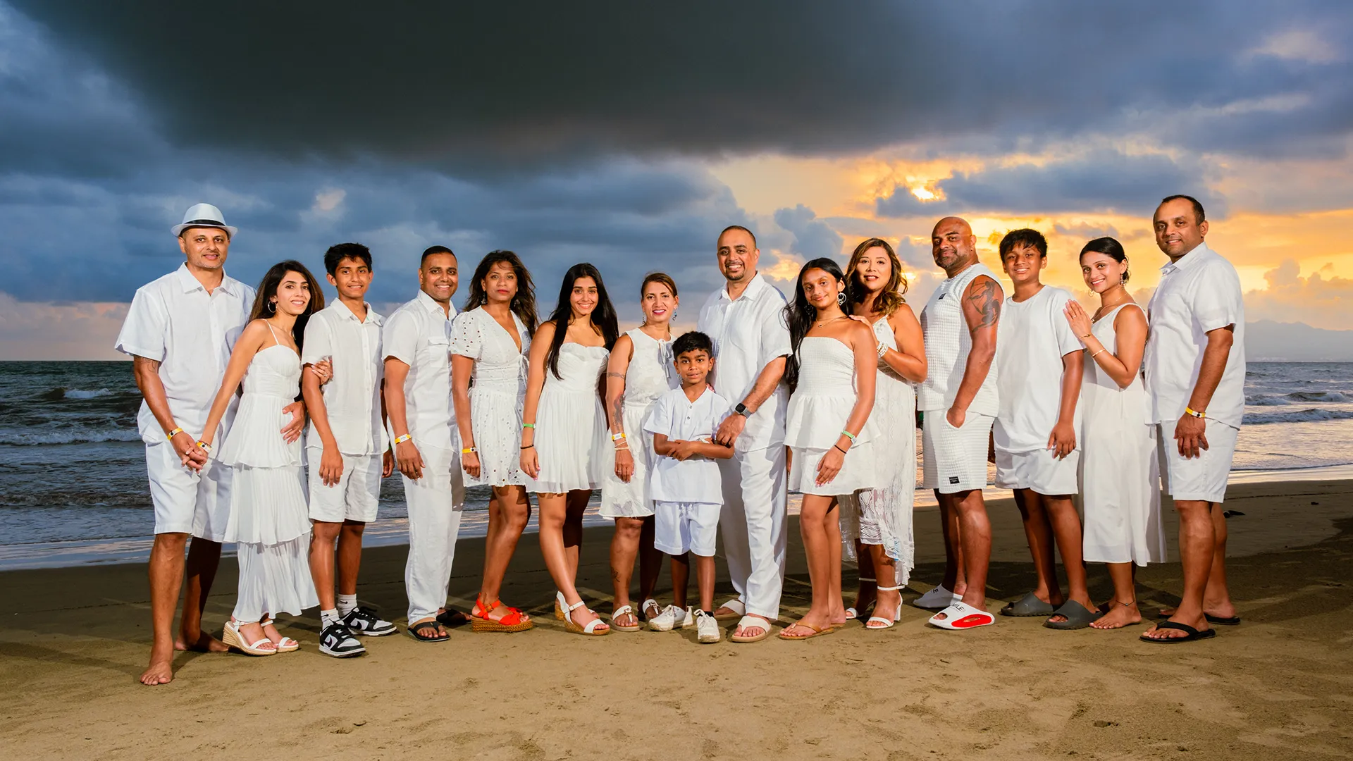 Extended family of sixteen posing together on the beach at sunset in Puerto Vallarta